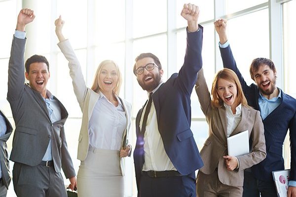 Group of ecstatic business partners looking at camera with raised arms